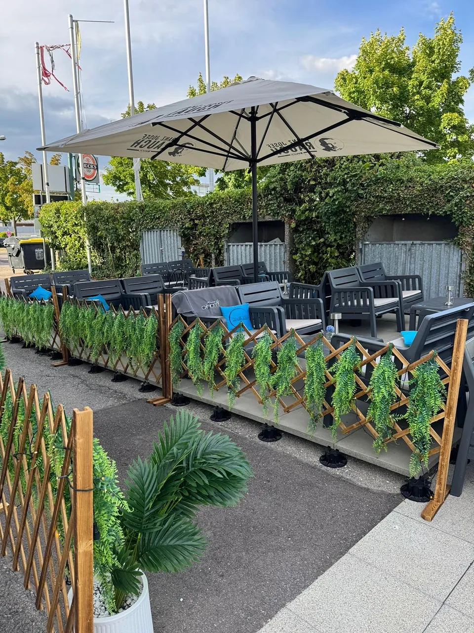 Terrasse mit Holzzaun, Grünpflanzen und Sonnenschirm