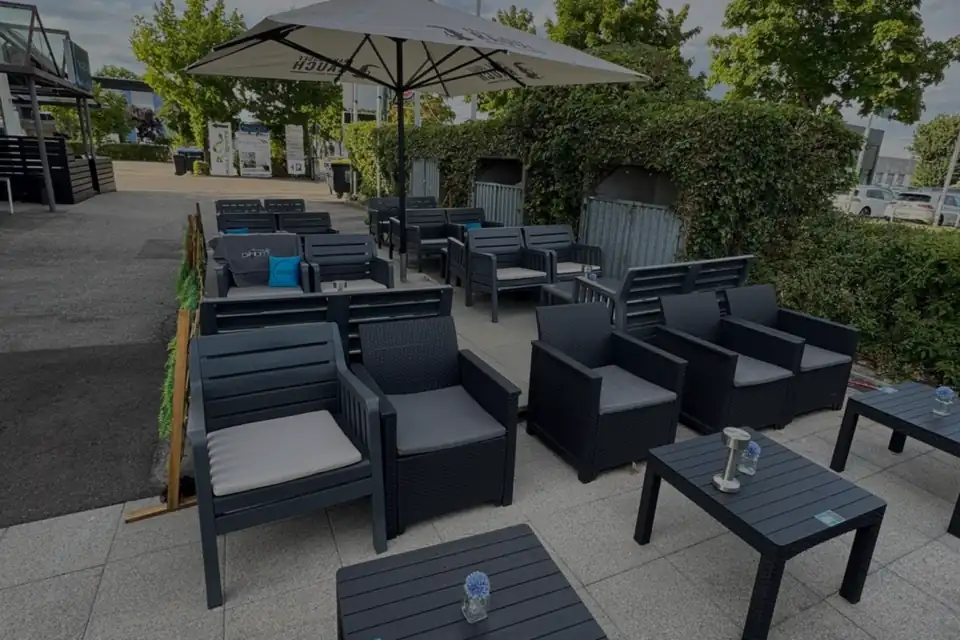 Terrasse des NUEVO mit Lounge-Sesseln und Sonnenschirm